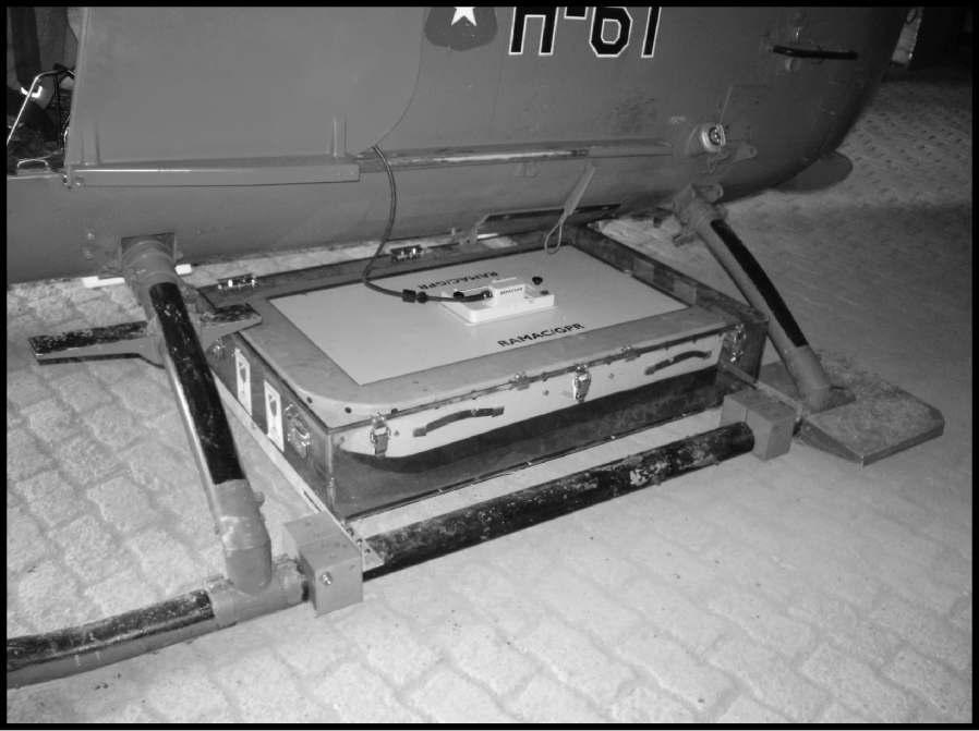 The shielded 100-MHz GPR unit mounted between the skids of a helicopter. Using this unit, a 10-ns radar pulse was generated at 35-ms intervals and received for 3700 ns at each shot point along Profiles A1-A3 across portions of the Fourcade Glacier.